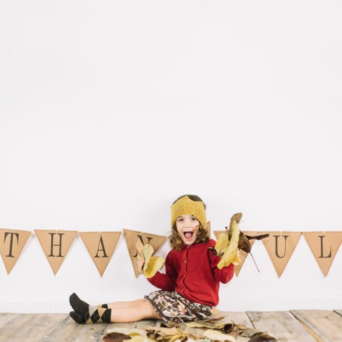 thanksgiving-concept-with-kid-playing-with-leaves